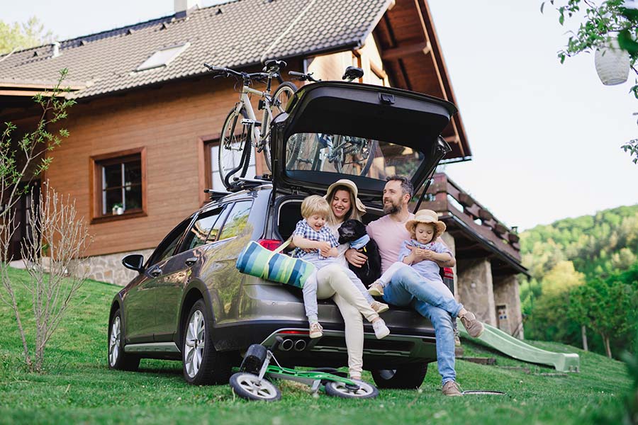 Contact - View of Excited Family with Two Kids and a Dog Sitting in the Trunk of Their Car During a Family Trip to the Countryside